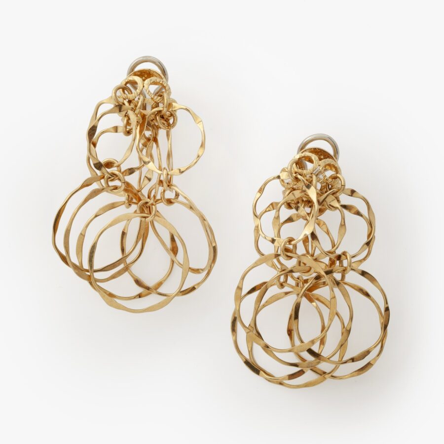 A pair of eighteen carat yellow gold earrings designed as a flowerhead clip on the ear, from which suspend many rings. Signed Cartier, made ca 1970.