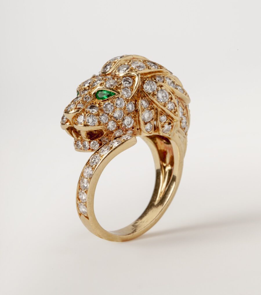An eighteen carat yellow gold ring designed as a lion’s head, set with diamonds and with emerald eyes. Made by Georges Lenfant, in Paris, ca 1970.