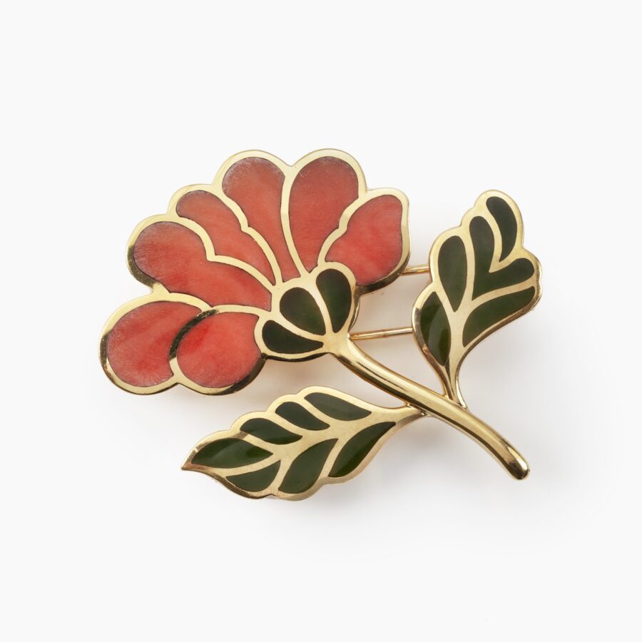 An eighteen carat yellow gold brooch designed as a flower branch, the flower inlayed with coral, the leaves with nephrite. Signed Tiffany & Co.