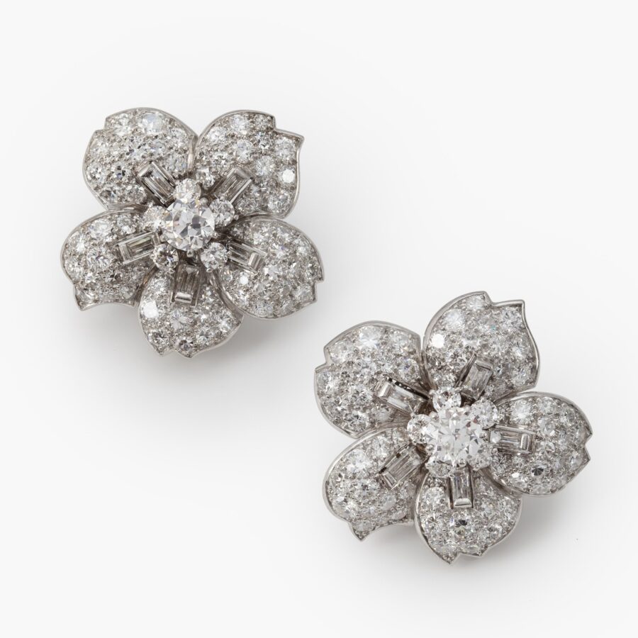 A pair of platinum clip earrings, each designed as a flower set with differently cut diamonds. Signed Cartier, made in London, ca 1950. In original case.