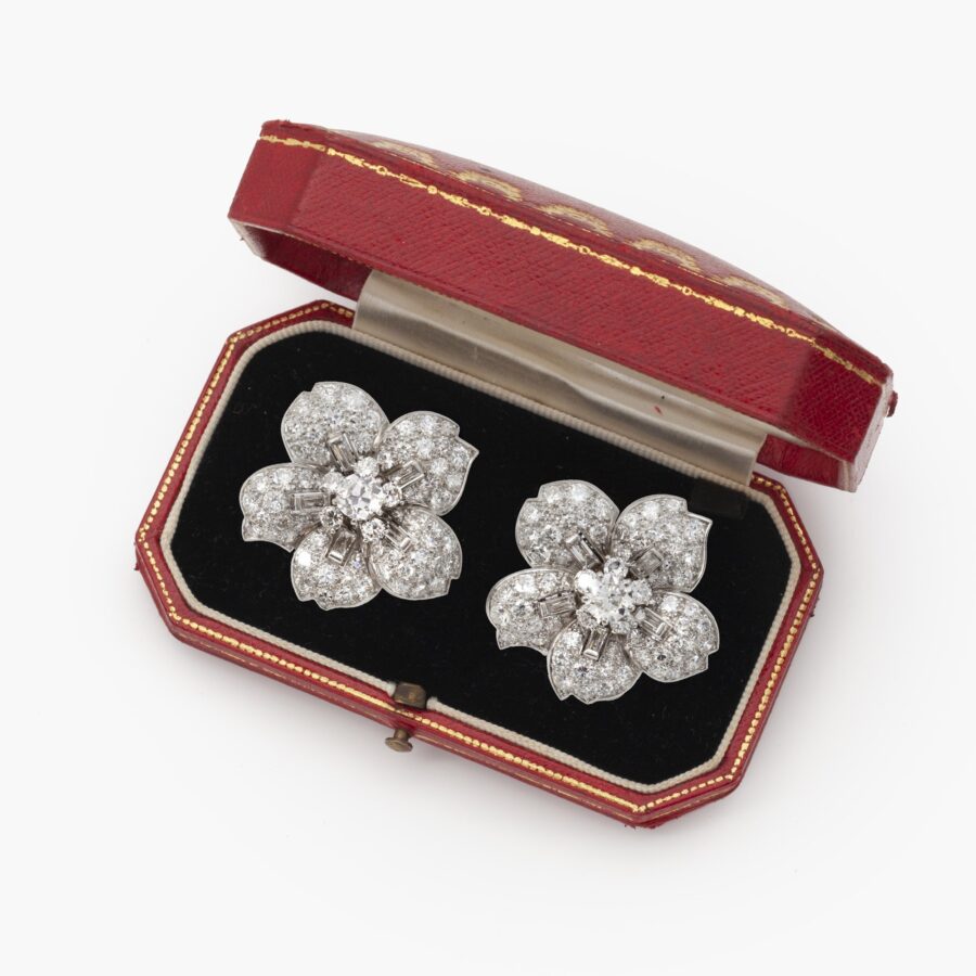 A pair of platinum clip earrings, each designed as a flower set with differently cut diamonds. Signed Cartier, made in London, ca 1950. In original case.