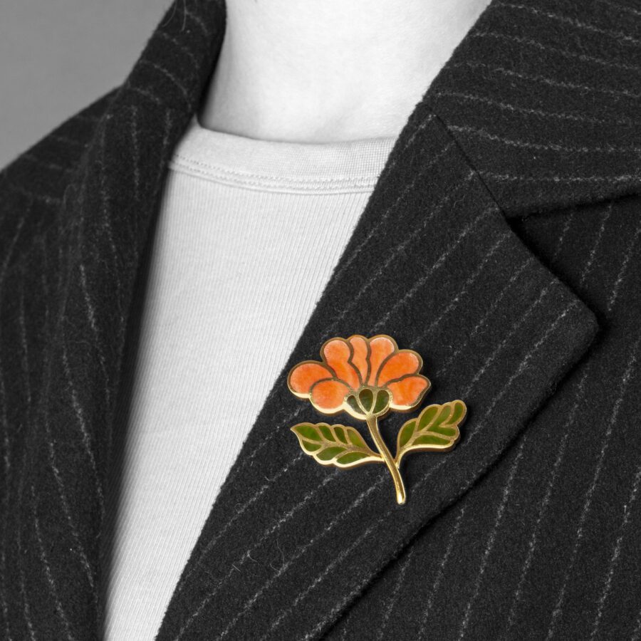 An eighteen carat yellow gold brooch designed as a flower branch, the flower inlayed with coral, the leaves with nephrite. Signed Tiffany & Co.