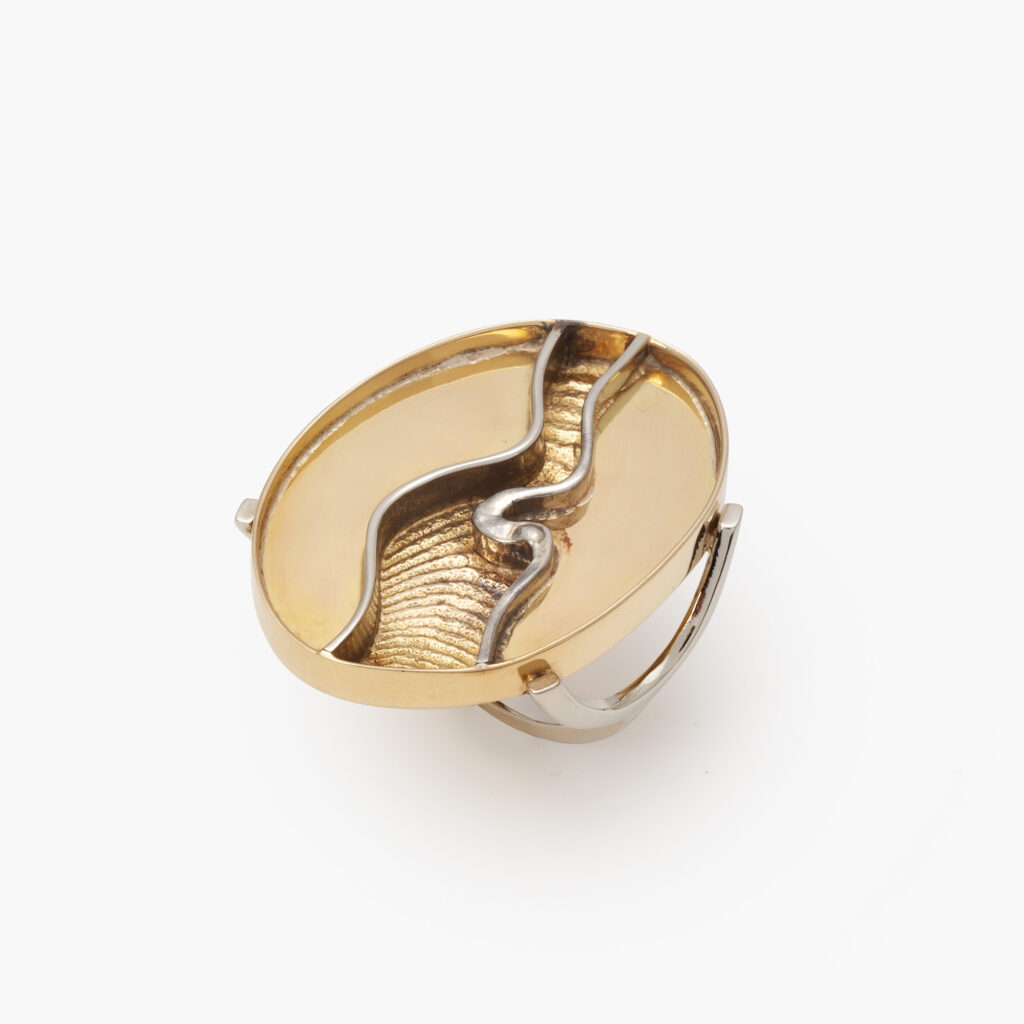 An eighteen carat yellow and white gold ring designed as a large oval head with sepia structure. Signed Arnaldo Pomodoro (Italy, 1926). Dated 1963.