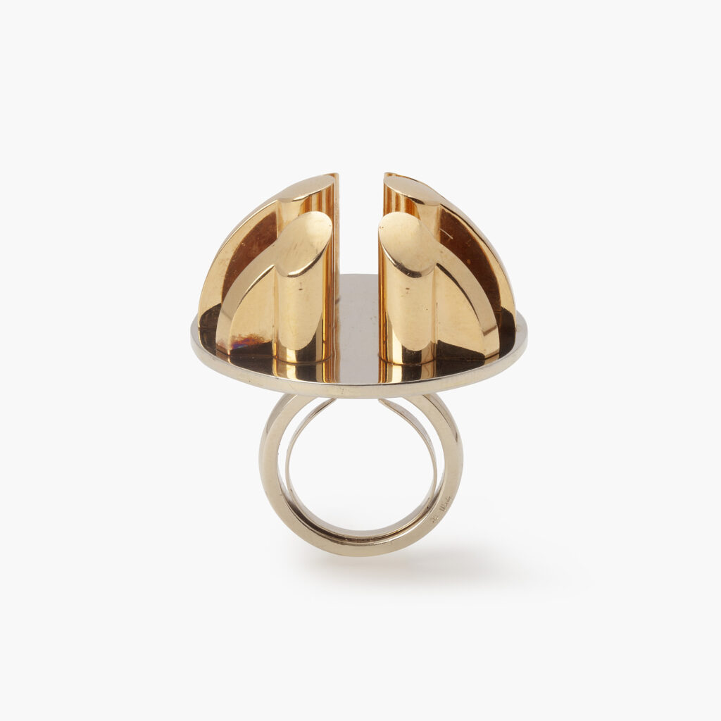 An eighteen carat yellow and white gold ring, six pillars are mounted on the round base. Signed Arnaldo Pomodoro, Italy. Numbered and dated 1970. 