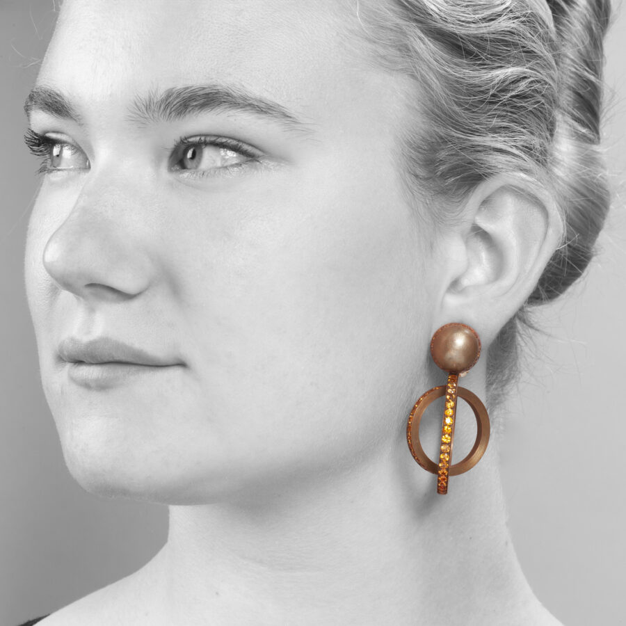 A pair of eighteen carat white gold and satiné copper earrings, set with round facetted orange garnets. Signed Hemmerle, made in Munich, early 21st century.