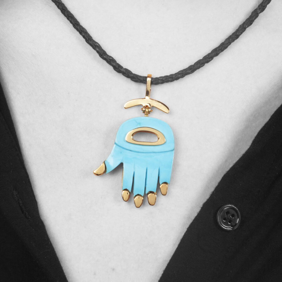 An eighteen carat yellow gold “Hamsa” pendant designed as a hand, inleyed with turquoise. Signed Aldo Cipullo, New York, ca 1970.