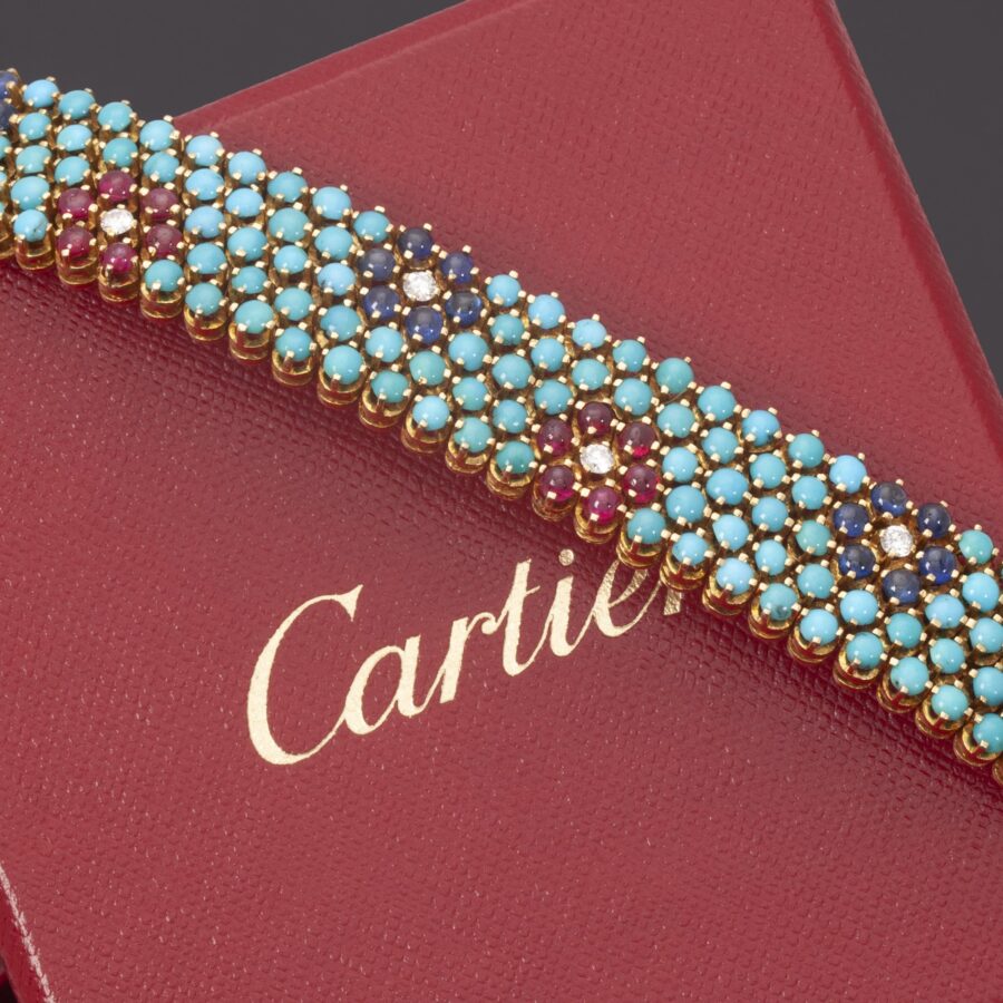 An eighteen carat yellow gold bracelet, set with turquoise, rubies, blue sapphires and diamonds. Signed Cartier, made in Italy, ca 1960 and numbered.