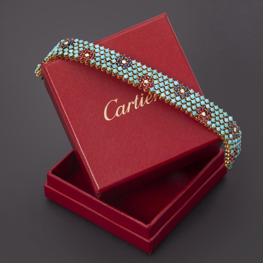 An eighteen carat yellow gold bracelet, set with turquoise, rubies, blue sapphires and diamonds. Signed Cartier, made in Italy, ca 1960 and numbered.