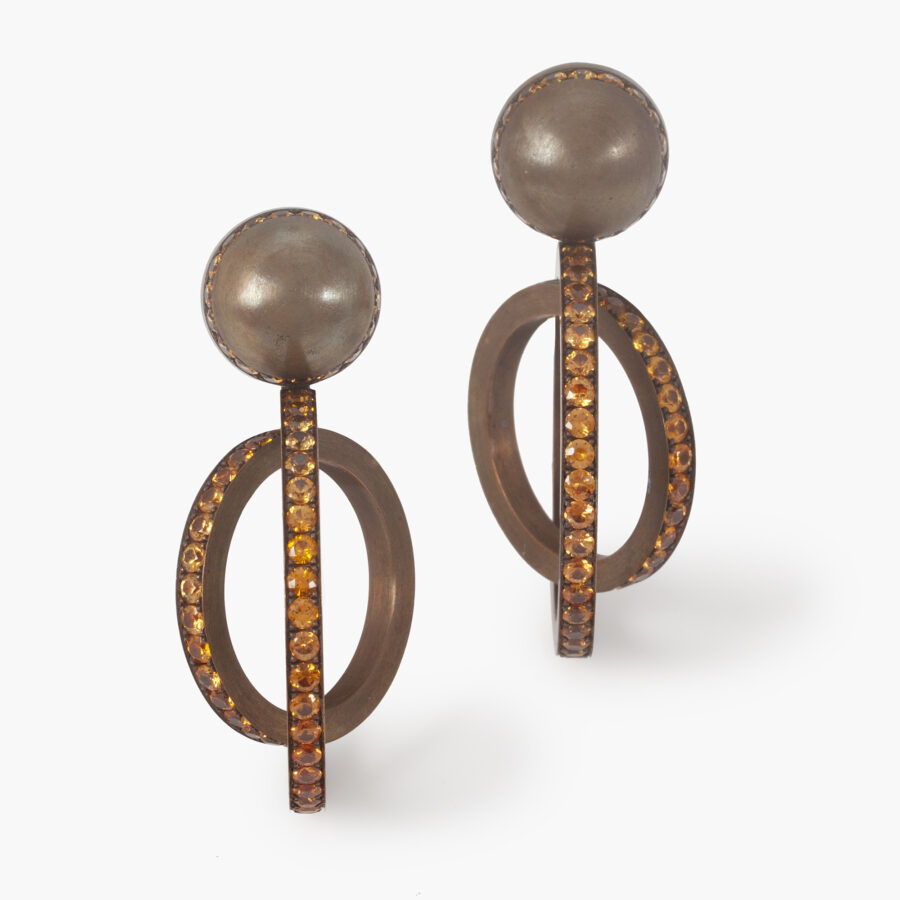 A pair of eighteen carat white gold and satiné copper earrings, set with round facetted orange garnets. Signed Hemmerle, made in Munich, early 21st century.