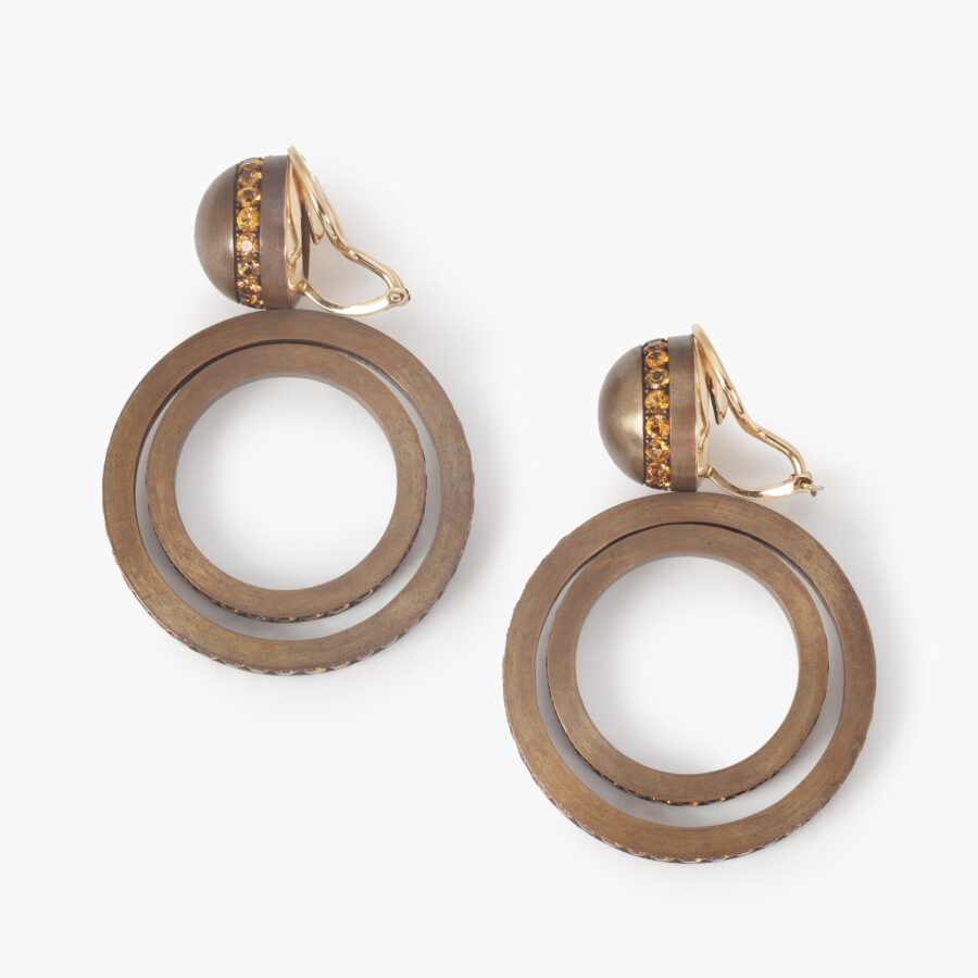 A pair of eighteen carat white gold and satiné copper earrings, set with round facetted orange garnets. Signed Hemmerle, made in Munich, early 21st century.