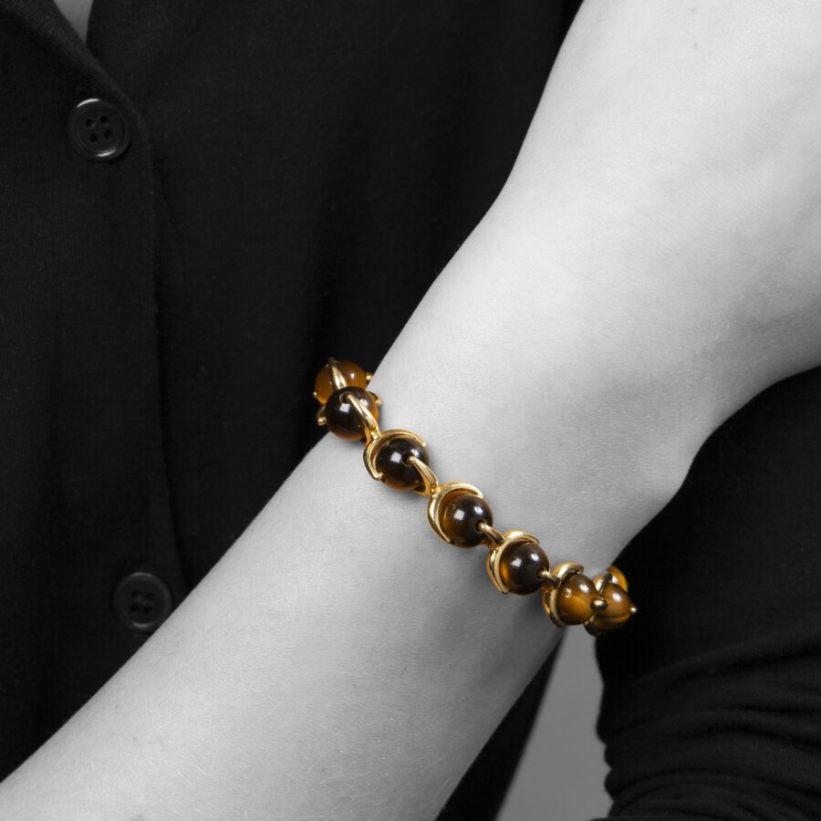 An eighteen carat yellow gold bracelet made of beads of tiger’s eye, connected by gold brackets. Signed Hermès, made in Paris, ca 1975.  