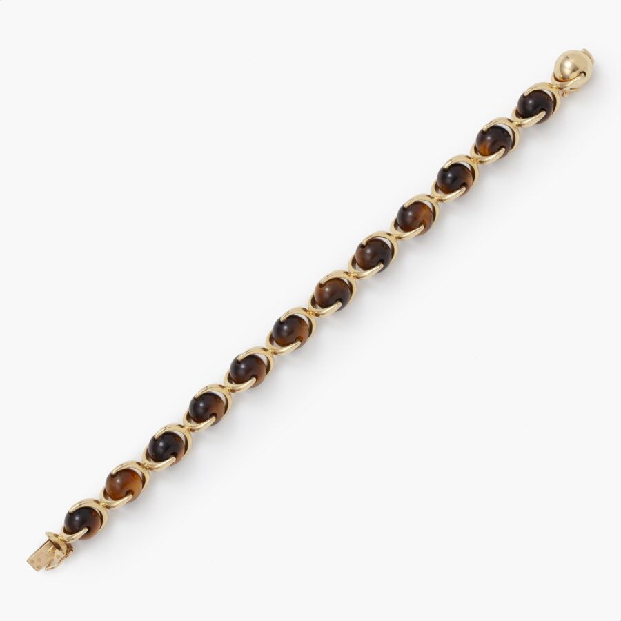 An eighteen carat yellow gold bracelet made of beads of tiger’s eye, connected by gold brackets. Signed Hermès, made in Paris, ca 1975.  