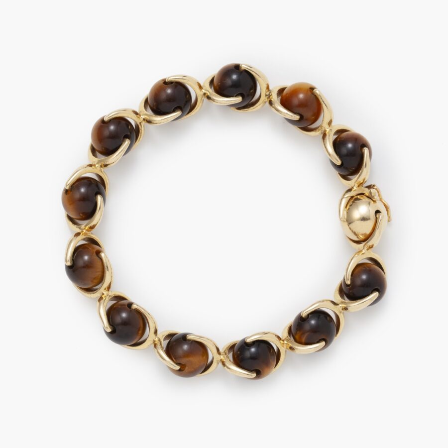 An eighteen carat yellow gold bracelet made of beads of tiger’s eye, connected by gold brackets. Signed Hermès, made in Paris, ca 1975.  