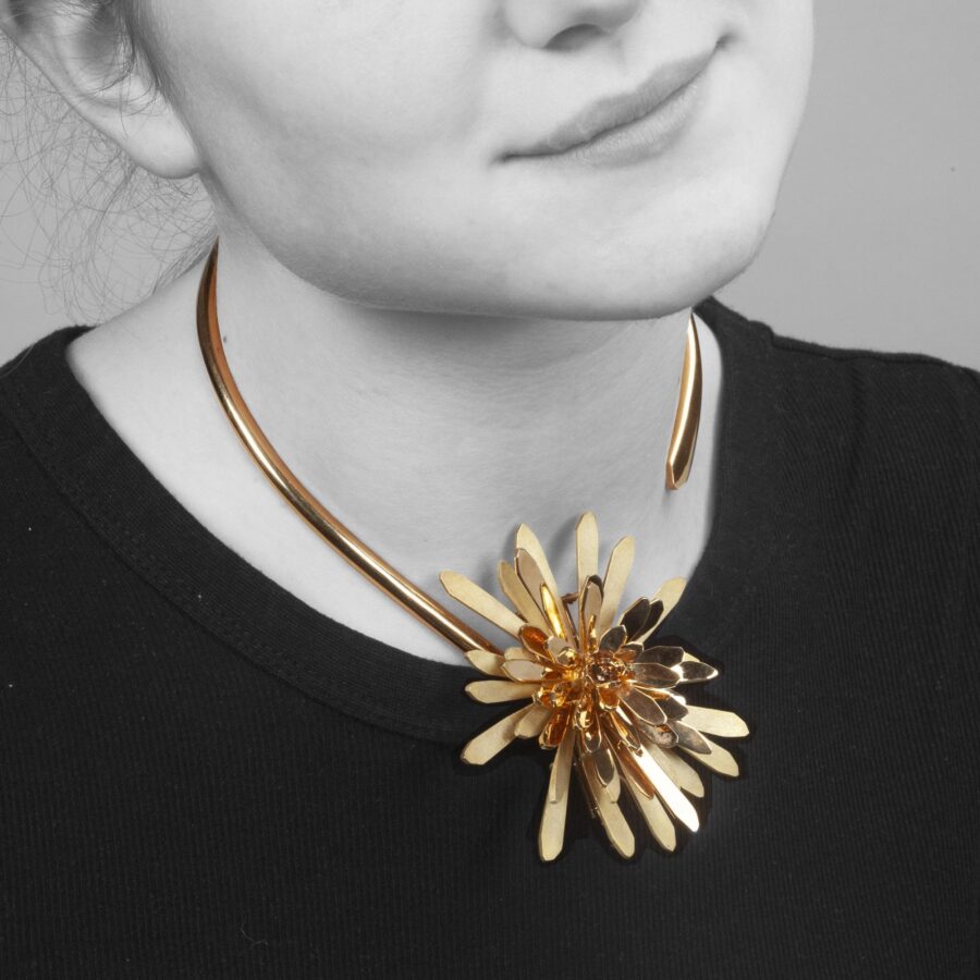 An eighteen carat yellow gold choker collar from the L’Arcade series with a large detachable flower wearable as a brooch. Signed Chaumet, Paris, ca 1970.